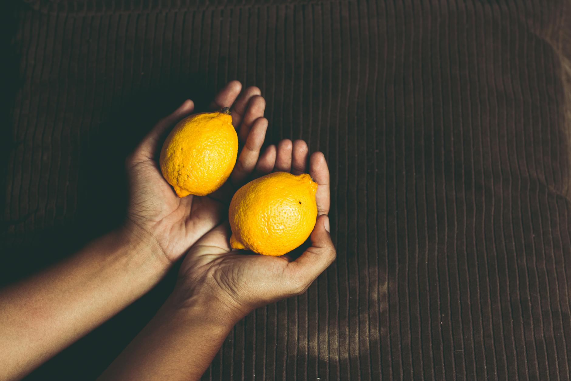 Hands cupping fresh lemons, representing the precision and sensitivity of building consistent orgasmic pleasure