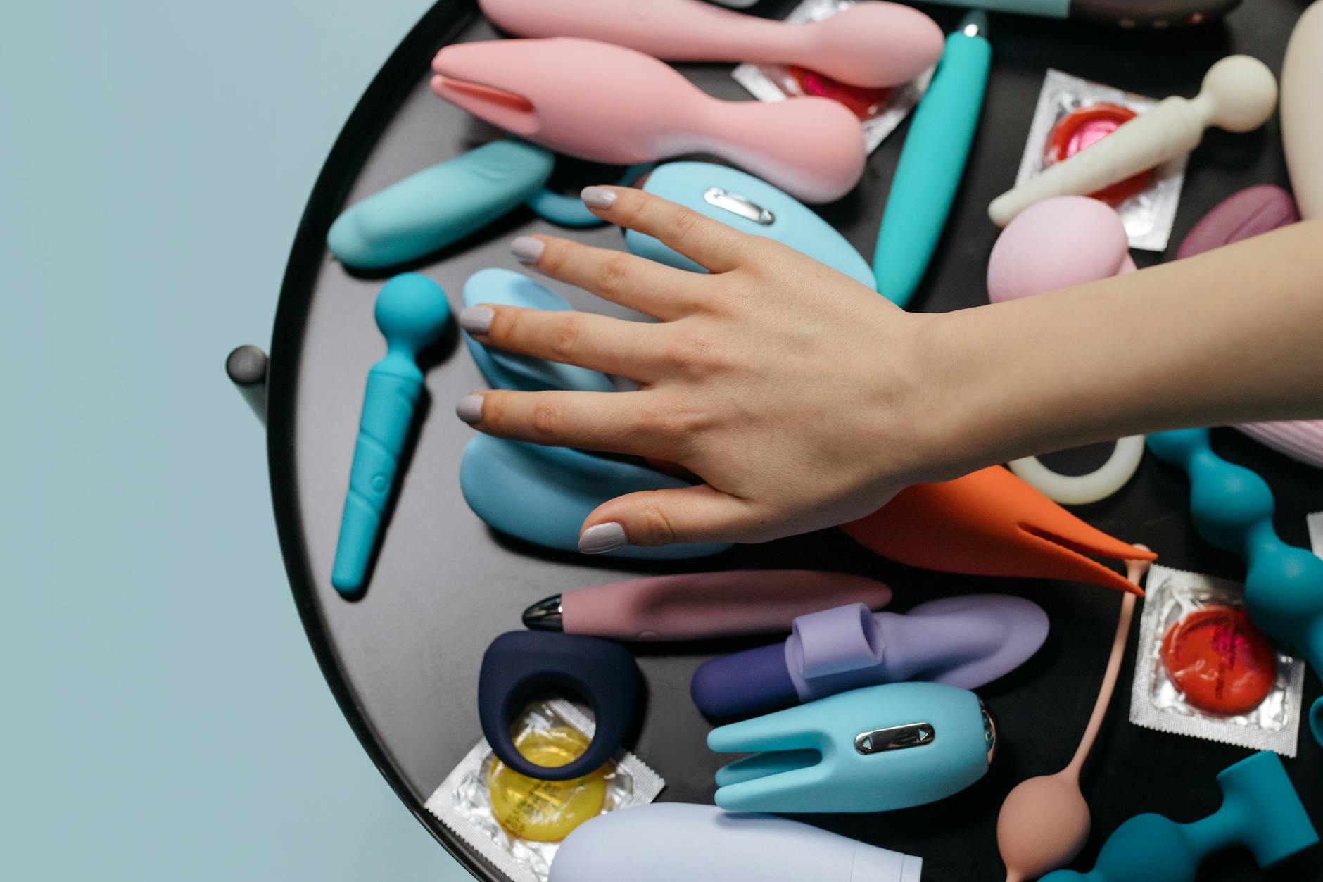 Young woman holding colorful clitoral vibrators against a purple background