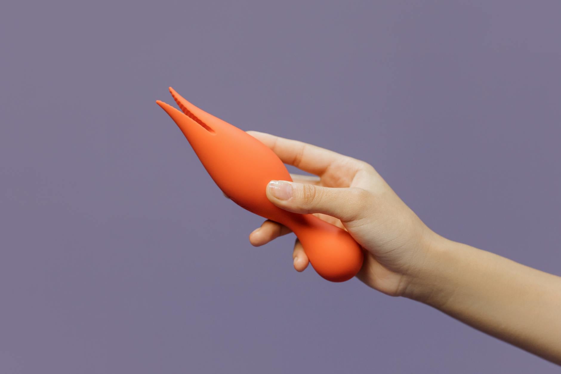 Hands holding a sleek blue lemon clitoral vibrator against a purple background